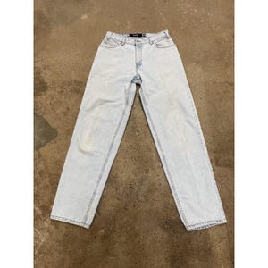 May include: Pale blue denim jeans with a straight leg. The jeans feature a classic five-pocket design, a button and zip fastening, and belt loops. The brand name "Bershka" is visible on the waistband.