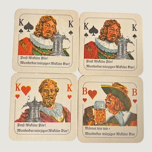 May include: Four square cardboard coasters featuring playing card designs with illustrations of historical figures holding beer steins. The text reads Prost Wicküler Pils! and Wunderbar würziges Wicküler Bier! or Männer wie wir. The coasters have rounded corners.