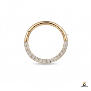 May include: A gold-colored, circular hinged earring with a row of small, clear gemstones set along the lower half. The earring is designed to be worn in a piercing. The brand name "GelinzaUS" is visible.