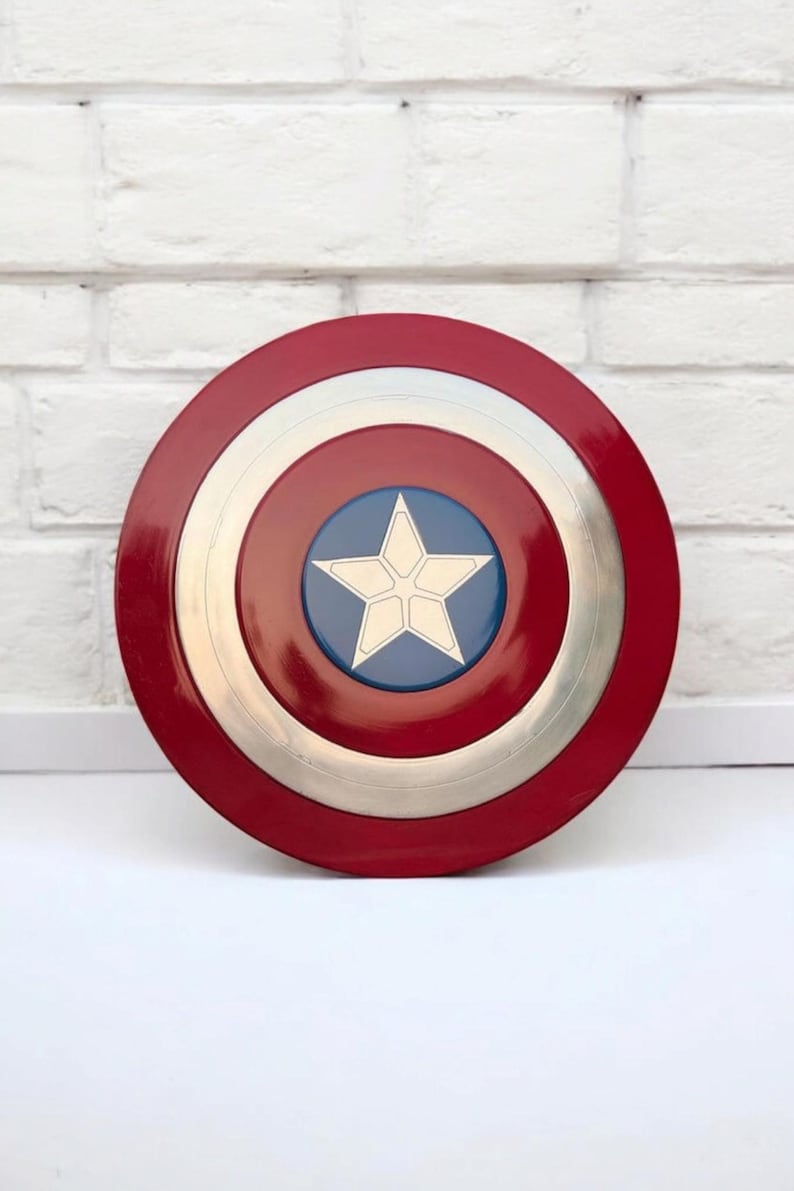 May include: A round shield with a red outer ring, a silver middle ring, and a blue center. A white star is in the center of the blue circle. The shield is a popular superhero accessory.