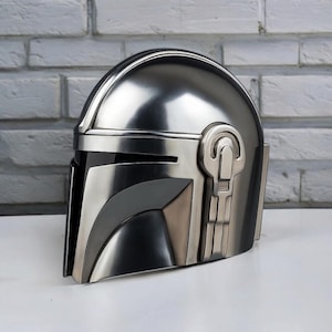 Puede incluir: Una taza de cer&aacute;mica blanca con un asa negra y el texto "But First, Coffee" en negrita negra. La taza se encuentra sobre un fondo borroso, sugiriendo un ambiente acogedor.