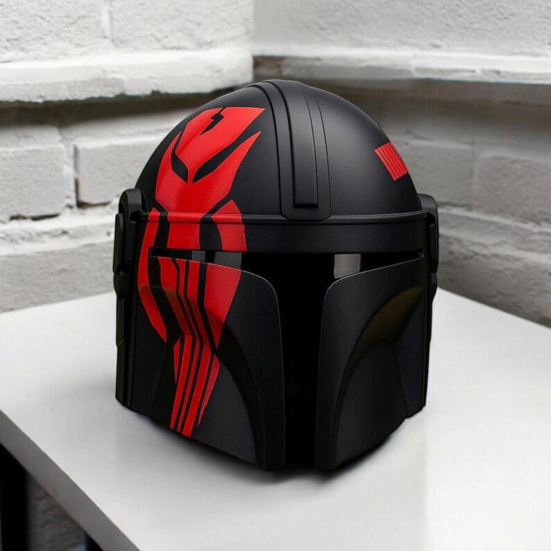 May include: Black helmet with red detailing. The helmet has a unique design with red patterns on the top and front, and a red stripe on the side. It includes a visor and is likely a costume or collectible item.