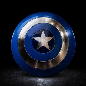 Op de afbeelding: Een blauw en zilver schild met een centrale witte ster. Het schild heeft een cirkelvormig ontwerp met concentrische ringen van blauw en zilver. De ster staat in het midden van het schild. Het schild is een rekwisiet.