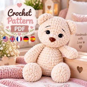 May include: A cream-colored plush teddy bear made of soft yarn with dark eyes and a brown nose. Above the bear, a decorative sign displays the text Crochet Pattern PDF, accompanied by five small circular flag icons representing different countries.