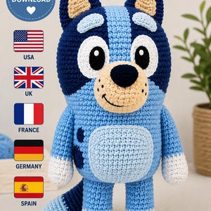 May include: A crochet pattern PDF download featuring a blue dog character with large white eyes, a tan muzzle, and dark blue ears. The design includes text reading CROCHET PATTERN PDF DOWNLOAD and flags for the USA, UK, France, Germany, and Spain.