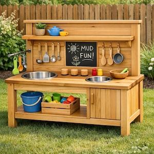 Könnte beinhalten: Eine hölzerne Outdoor-Spielküche mit einer Tafel mit der Aufschrift "MUD FUN!". Sie hat zwei Edelstahlspülen, ein Regal mit einer blauen Teekanne und einer gelben Tasse sowie hängendes Kochgeschirr. Ein blauer Eimer und eine Holzkiste mit Spielzeug befinden sich darunter.