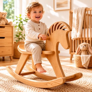 May include: A light-coloured wooden rocking horse with a smooth, curved seat, a stylised mane featuring vertical cutouts, and two curved rockers at the base, designed for a child to sit on while holding onto the horizontal wooden handle.