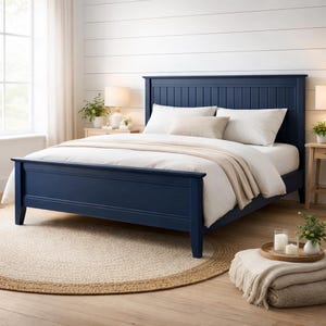 Könnte beinhalten: Ein marineblauer Bettrahmen mit einem Latten-Kopfteil ist der Mittelpunkt dieser Schlafzene. Das Bett ist mit weißer Bettwäsche und einer beigen Decke bezogen. Ein runder Jute-Teppich liegt unter dem Bett, und ein kleiner Nachttisch mit einer Lampe ist sichtbar.