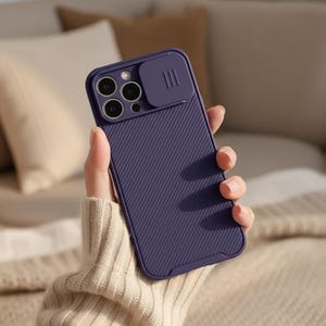 May include: A dark purple phone case with a sliding camera cover. The case has a textured, ribbed design on the back and a raised edge around the camera lenses. The case is held in a hand.
