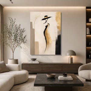 Può includere: Stampa artistica astratta raffigurante una donna con cappello e abito. L'opera d'arte utilizza toni oro, neri e beige. La silhouette della donna è il punto focale, con un abito fluente e un cappello a tesa larga. Lo sfondo presenta forme geometriche e pennellate.