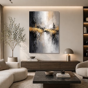 Puede incluir: Impresión en lienzo de arte abstracto con una paleta de colores dorados, negros y grises. La obra de arte presenta un diseño texturizado y en capas con acentos dorados y pinceladas verticales. La pintura se exhibe en un salón moderno.