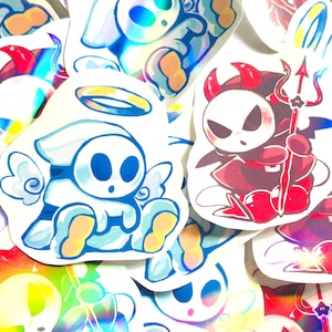 May include: A collection of colorful stickers featuring cartoon characters. One sticker depicts a blue and white angel with a halo, while another shows a red devil with a trident. The stickers have a glossy finish and are scattered across a white surface.