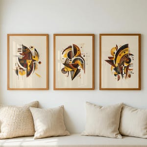 以下が含まれることがあります： 3つの額入り抽象芸術プリント。各プリントは、クリーム色の背景に茶色、黄色、黒の色合いの形で幾何学的なデザインを特徴としています。プリントは木製のフレームに入っており、クッション付きの白いベンチの上に表示されています。
