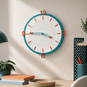 Op de afbeelding: Een ronde wandklok met een blauwgroene buitenrand, een witte wijzerplaat met een textuur van een rasterpatroon en oranje cijfers op de posities 12, 3, 6 en 9. De klok heeft blauwgroene wijzers met oranje punten en oranje streepjesmarkeringen.