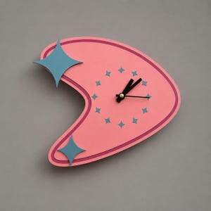 Può includere: Un orologio da parete a forma di boomerang in rosa opaco con un bordo rosa scuro. Il quadrante presenta piccoli indicatori delle ore a forma di stella blu disposti in cerchio, con due grandi stelle blu sul lato sinistro e lancette nere.