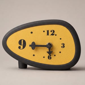 Peut inclure: Une horloge de table asymétrique avec un cadre noir mat et un cadran jaune texturé. L'horloge présente les chiffres noirs 3, 6, 9 et 12, avec des points noirs pour les autres heures. Deux aiguilles noires sont placées au centre du cadran.