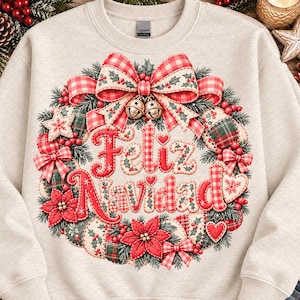 May include: A beige crewneck sweatshirt featuring a large, central graphic of a Christmas wreath. The wreath is decorated with red and white checkered bows, holly, berries, poinsettias, and bells. The text Feliz Navidad is in the center.