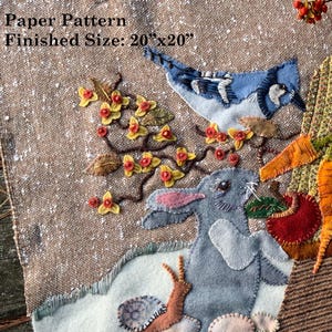 May include: A textile art piece featuring a harvest scene with a blue jay, rabbit, chipmunk, and pheasant. The design includes a cornucopia filled with carrots, apples, and flowers. Finished size is 20"x20".
