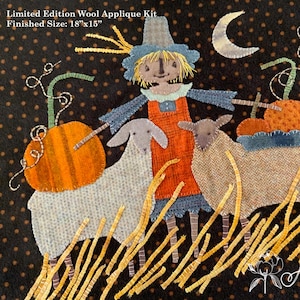 May include: A wool applique kit with a finished size of 18"x15". The image features a scarecrow, two sheep, and pumpkins in a fall harvest scene. The background is black with brown polka dots, and a crescent moon is visible.