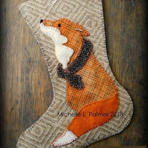 Peut inclure: Une chaussette de Noël en feutre avec un motif de renard. Le renard est orange et blanc avec un nœud papillon noir. La chaussette est beige avec un motif en losange. Le texte "Merry Christmas" est en haut de la chaussette. Le texte "Michelle L. Palmer 2018" est en bas de la chaussette. Le texte "For your personal use only 2018 Stocking pattern" est en bas de l'image.