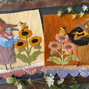 Op de afbeelding: Twee vilten kunstwerken met grillige vogel figuren met hoeden, naast zonnebloemen en bijen. Eén stuk heeft een beige achtergrond, de andere is oranje. Beide hebben geschulpte randen en de handtekening van de kunstenaar.