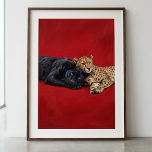 May include: A framed wall art print featuring a black panther and a spotted cheetah lying together on a solid, vibrant red background. The animals are positioned side-by-side, with the panther on the left and the cheetah on the right.