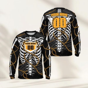 May include: Black long-sleeve shirt featuring a white skeleton design with barbed wire accents. The shirt includes a yellow and black shield with the text "YOUR NAME" and the number "00". The back of the shirt also displays the skeleton design and the number "00".