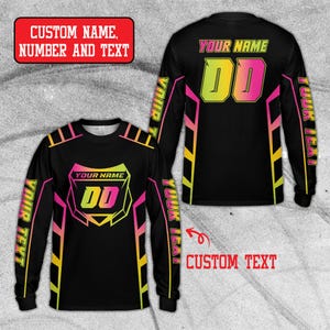 Peut inclure: Maillot noir à manches longues avec des accents rose néon et jaune. Le maillot affiche le texte "YOUR NAME" et "DD" à l'avant et à l'arrière. Les manches portent l'inscription "YOUR TEXT". L'image comprend également le texte "CUSTOM NAME, NUMBER AND TEXT" et "CUSTOM TEXT".