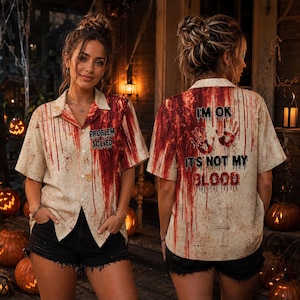 May include: A short-sleeved button-down shirt with a beige base and a red blood-splatter pattern. The front features the text "PROBLEM SOLVED". The back displays two red handprints and the text "I'M OK IT'S NOT MY BLOOD" in a dripping font.