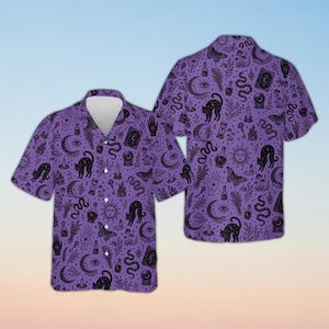May include: A short-sleeved button-down shirt in a vibrant purple hue, featuring an all-over black ink-style print. The pattern includes illustrations of cats, crescent moons, suns, snakes, moths, crystal balls, candles, and hands with symbols.