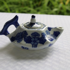 May include: A small, white teapot with a blue floral design. The teapot has a lid and a spout.