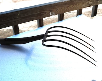 Forcone da fattoria dei primi del '900 con cinque rebbi sottili, riutilizzato come materiale per decorazioni da giardino.