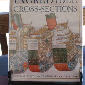 Könnte beinhalten: Das Buch "Stephen Biesty's Incredible Cross-Sections" wird gezeigt. Es zeigt detaillierte Querschnittsillustrationen von Schiffen. Das Buch wird in einem schwarzen Ständer gehalten. Der Text unten lautet: "Mit zwei ausklappbaren Bildern von fast 1 Meter Länge!"