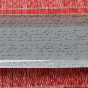 May include: A rectangular glass dish with a white background and a pattern of blue handwritten text. The dish is perfect for serving snacks or holding jewelry.