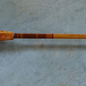 K&ouml;nnte beinhalten: Eine Angelrute aus Holz mit einem braunen und beigefarbenen Griff und einem braunen und beigefarbenen K&ouml;rper.