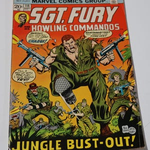 May include: A vintage comic book cover for Sgt. Fury and His Howling Commandos. The cover features a large illustration of a soldier in a green uniform holding two machine guns. The title "Jungle Bust-Out!" is at the bottom.