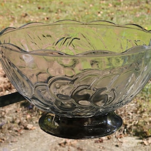 May include: A clear glass punch bowl with a silver base and a textured design. The bowl has a scalloped rim and is perfect for serving punch or other beverages.