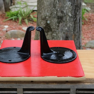 Peut inclure: Deux supports d'étagère en métal noir avec un design incurvé. Les supports sont sur une surface rouge.