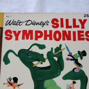 May include: A vintage Dell comic book cover featuring Walt Disney's Silly Symphonies. The cover art depicts a green, cartoonish creature playing a flute, with a smaller green creature in a top hat and a bird in the background. The title "Walt Disney's Silly Symphonies" is printed in red and black lettering.