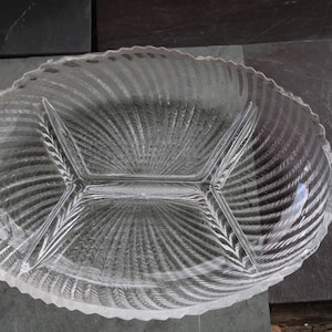 Puede incluir: Fuente de vidrio transparente con tres compartimentos. La fuente ovalada tiene un patrón texturizado en forma de abanico que irradia desde el centro. El borde tiene un borde festoneado. Ideal para servir aperitivos.