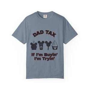 Könnte beinhalten: Ein blaues Kurzarm-T-Shirt mit dem Text "DAD TAX" über vier schwarzen Cartoon-Symbolen. Darunter steht der Satz "If I'm Buyin' I'm Tryin'". Das Shirt besteht aus einem weichen Material.