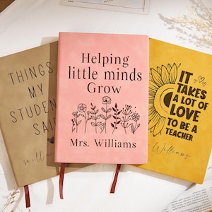 Puede incluir: Tres cuadernos con citas inspiradoras para profesores. Uno es de color canela con "THINGS MY STUDENT SAID", otro es rosa con "Helping little minds Grow", y el tercero es amarillo con "IT TAKES A LOT OF LOVE TO BE A TEACHER".