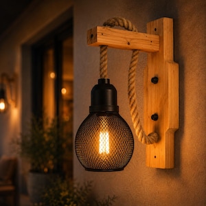 May include: A rustic wall sconce featuring a black metal mesh globe light fixture. The light hangs from a thick rope and is mounted on a wooden plank. The fixture is illuminated, casting a warm glow.