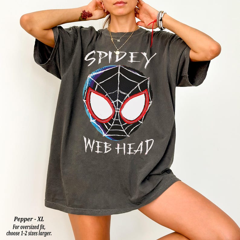 May include: Dark gray oversized t-shirt featuring a graphic of Spider-Man's mask with the words "SPIDEY" and "WEB HEAD" in white. The shirt is a Pepper XL size, designed for an oversized fit.