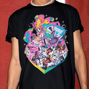 May include: A black short-sleeve t-shirt featuring a vibrant, multi-colored graphic print of various animated characters. The design includes pink, blue, and yellow accents arranged in a heart-shaped composition with small star details throughout the illustration.