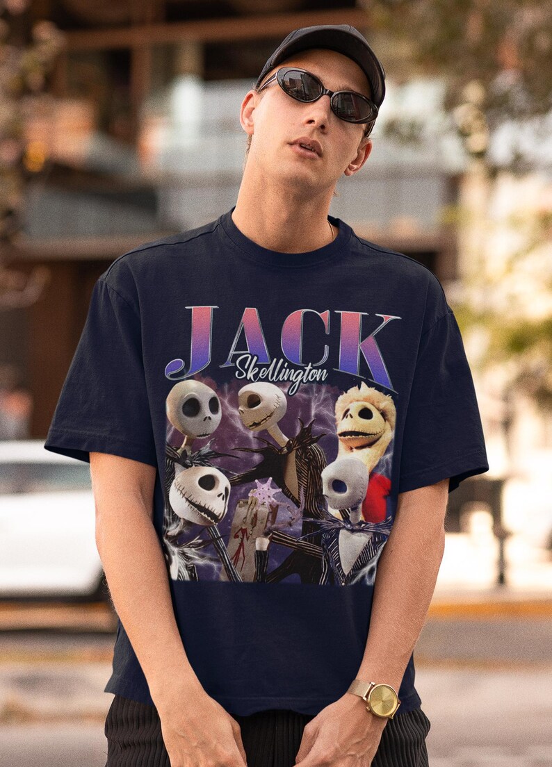 May include: Navy blue t-shirt featuring a graphic of Jack Skellington from The Nightmare Before Christmas. The design includes the text "JACK Skellington" in a gradient font, and images of Jack's face.