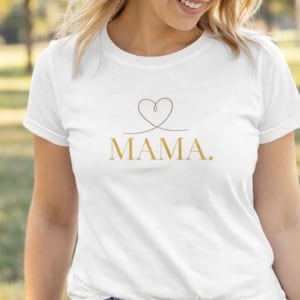 Könnte beinhalten: Weißes T-Shirt mit einem goldenen Herz-Design über dem Wort "MAMA." Das Shirt besteht aus einem weichen Material und hat kurze Ärmel. Der Text ist in einer einfachen, eleganten Schriftart gehalten.
