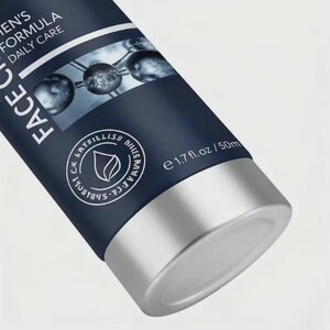 May include: A close-up of a dark blue tube of face cream with silver accents. The tube has white text that reads "MEN'S FORMULA DAILY CARE FACE". The bottom of the tube is silver and contains 1.7 fl. oz / 50ml.