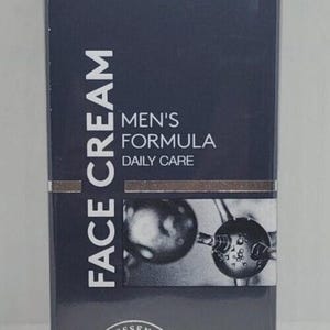May include: A dark gray box of Particle Face Cream. The box features the brand name "PARTICLE" and the text "Aesthetic Science For Men." It also includes "Men's Formula Daily Care" and "Face Cream." The product contains 1.7 fl oz / 50ml.