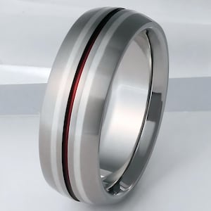May include: A silver titanium ring with a red and white inlay. The ring has a beveled edge and a polished finish.